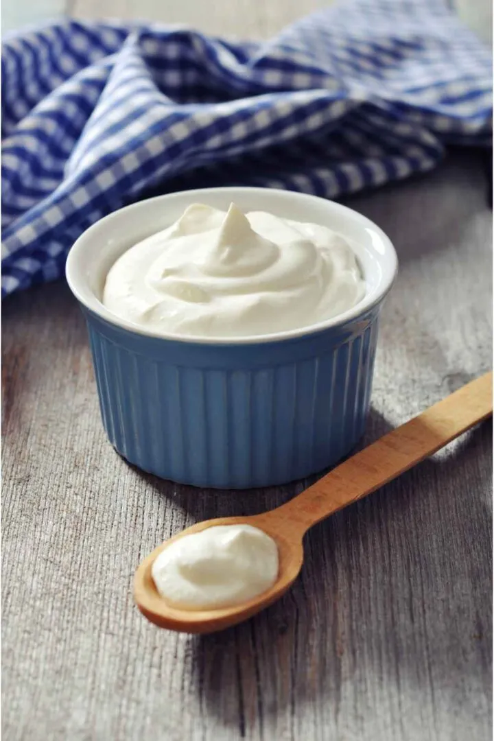 yogur griego en una taza y cuchara de madera